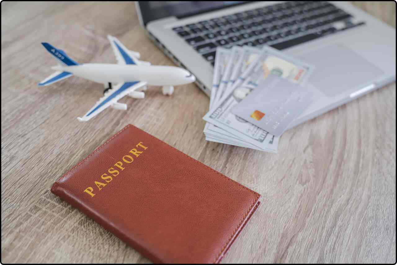 Person booking a flight online using a laptop,Airline tickets and a passport placed on a wooden table, ready for travel.